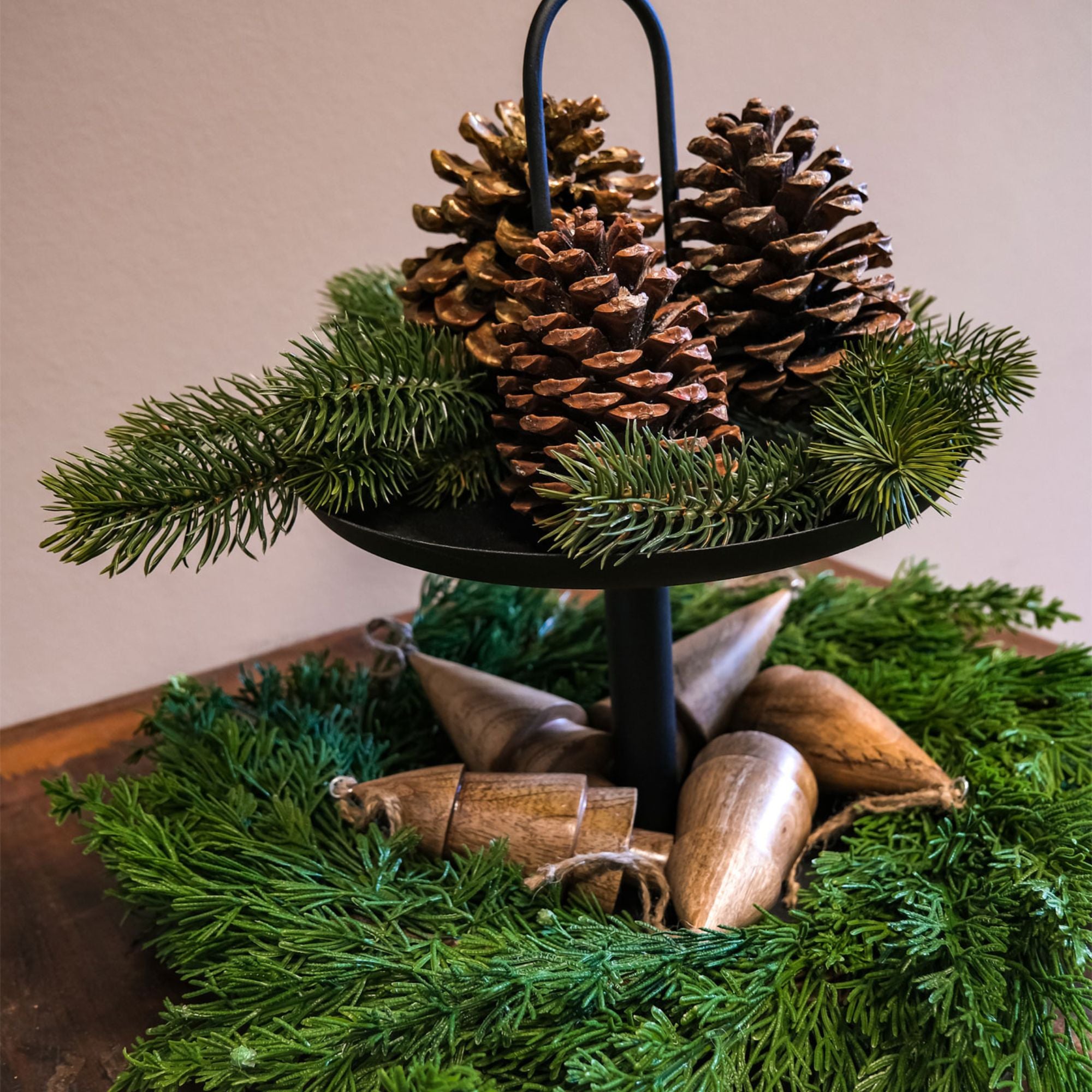 Etagere mit Tannezweigen und Tannenzapfen und Baumschmuck aus Holz für Weihnachten